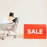 Keranjang belanja mini berisi produk dengan tanda sale, menggambarkan konsep promo produk dan strategi promosi penjualan